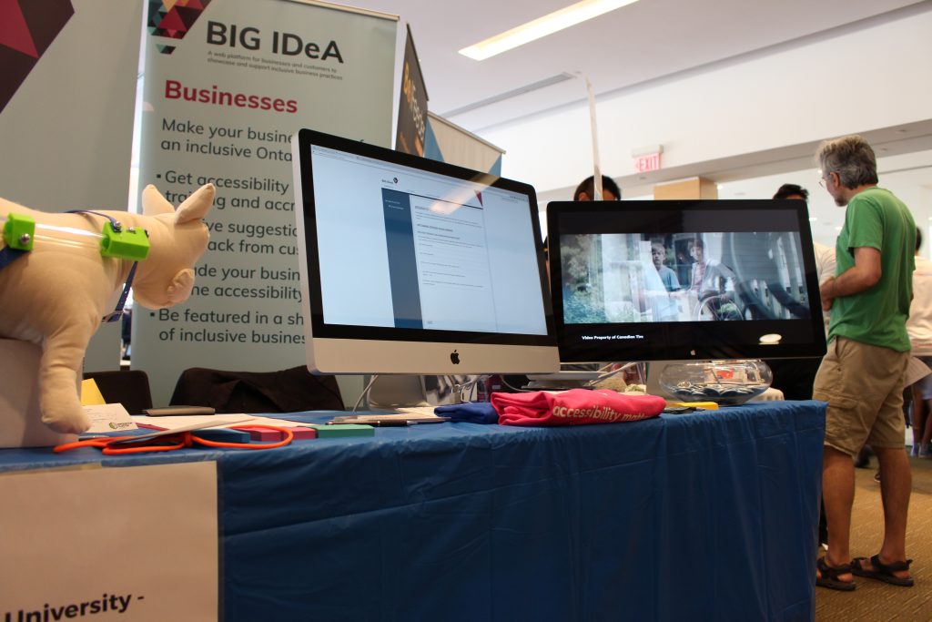 Photo of the BIG IDeA display booth at the 2017 Maker Festival. Two large screens showcasing the BIG IDeA website and video.