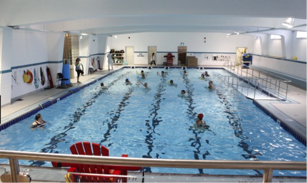 This image is of a photograph that shows an indoor swimming pool, with ramp access into the water.