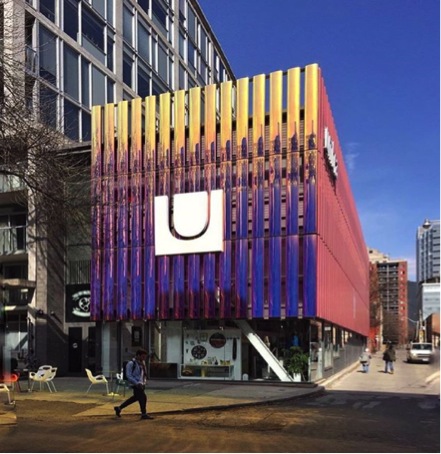 This image is a photograph of the outside of the Umbra building taken during the daytime and includes the chairs outside that can be used by the community.